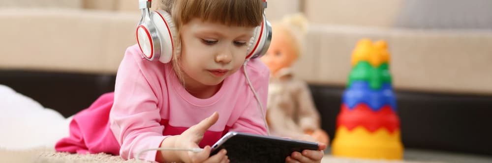 Dziewczynka w słuchawkach słuchająca audiobooka.