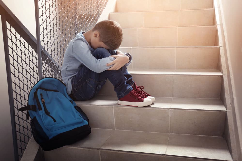 Dziecko,. które nie chce iść do szkoły – a siedzi na schodach i płacze.