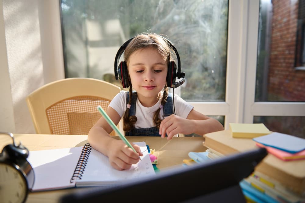 dziewczynka uczy się ze słuchawkami na uszach 