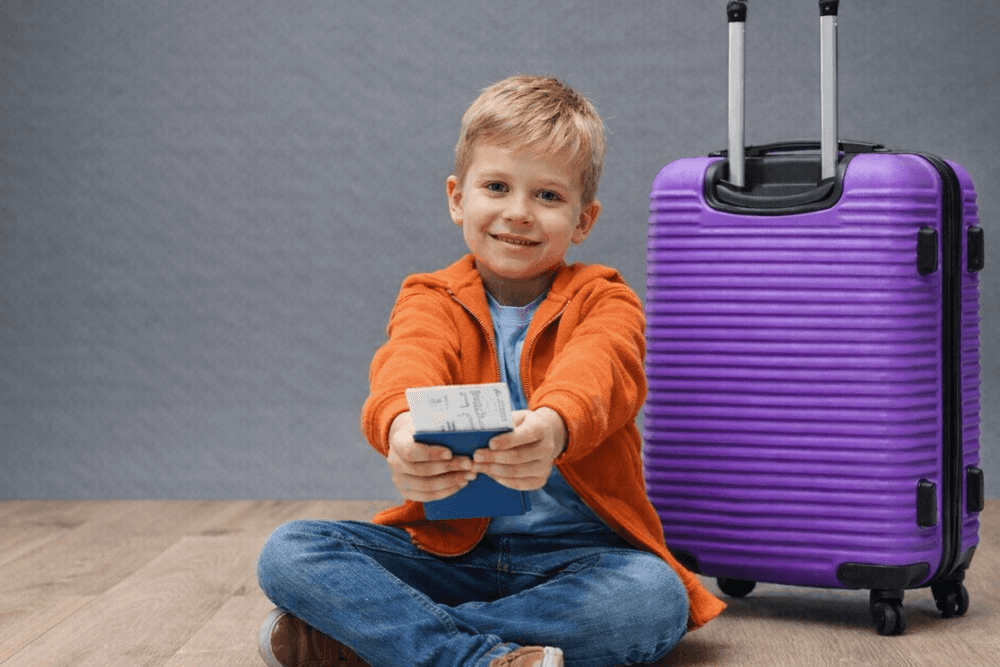 chłopiec z walizką trzymający w dłoni dokument tożsamości