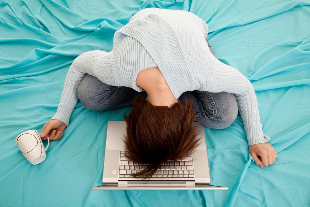 zmęczona kobieta z głową na laptopie