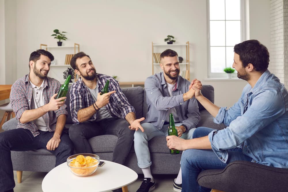 czterech mężczyzn z piwami siedzących na kanapie czterech mężczyzn z piwami siedzących na kanapie