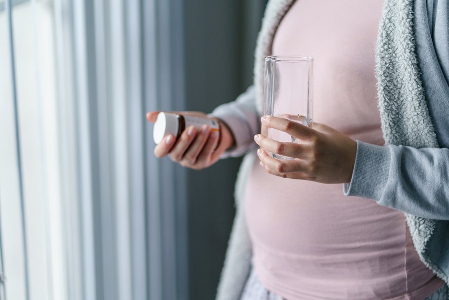 Kobieta w ciąży przyjmująca cholinę w tabletkach.