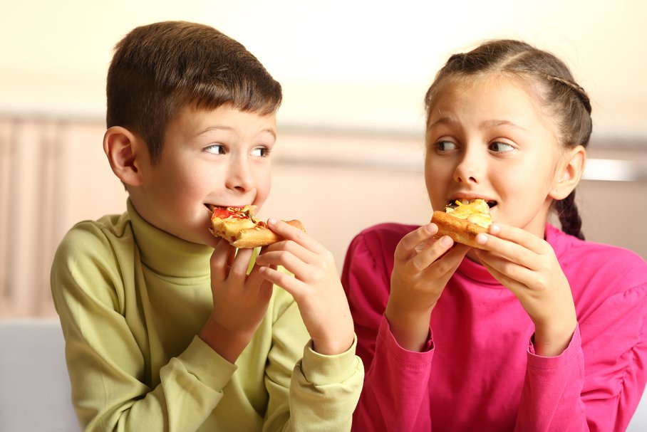 Chłopiec i dziewczynka jedzący pizzę.
