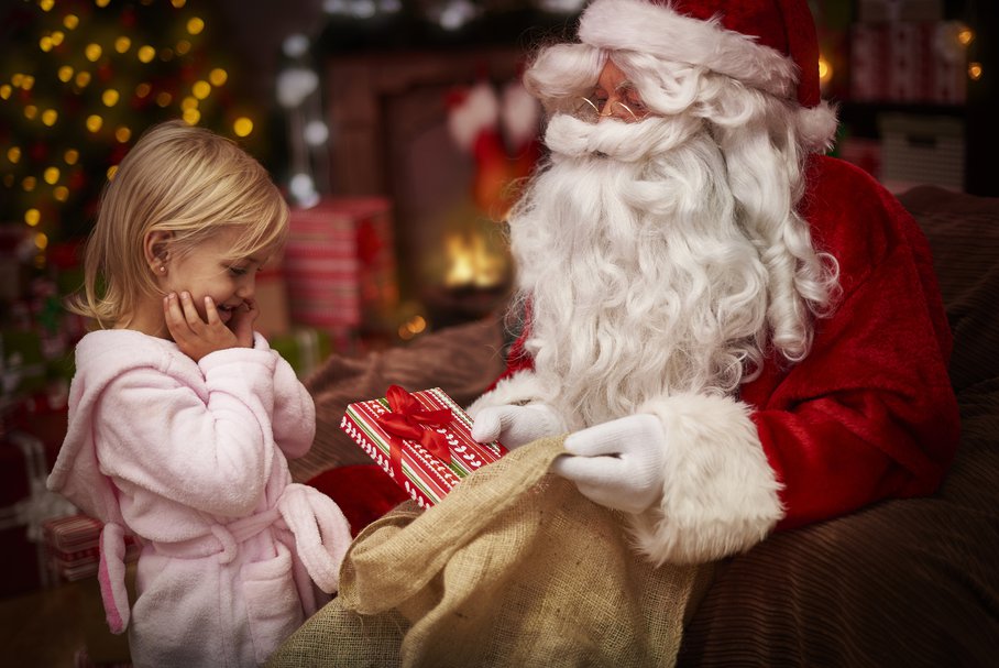 Święty Mikołaj wręczający prezent małej dziewczynce.