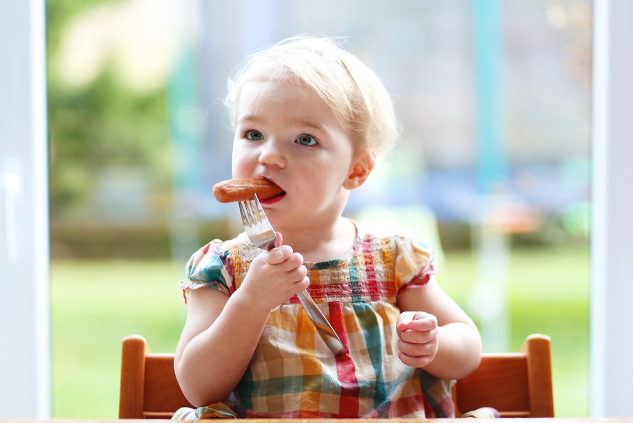 Mała dziewczynka jedząca parówkę.