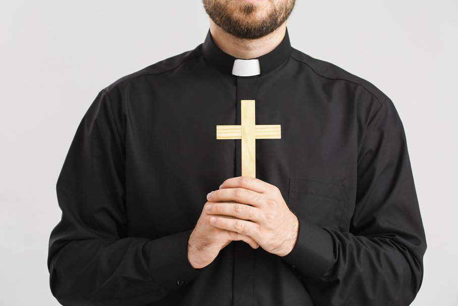 Ksiądz katolicki trzymający krzyż.