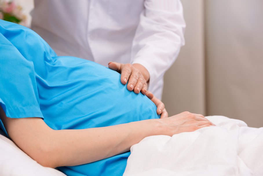 Lekarz dotykający brzucha kobiety w ciąży.